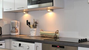 A modern kitchen with a Bosch dishwasher, a coffee maker, and a basket of kitchen utensils. - Ground Floor 3-Room Apartment with Terrace & Garden, 5 min to Beach, A/C, Parking, Villeneuve-Loubet (Villeneuve-Loubet)