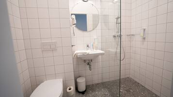 Baño con inodoro, lavabo, espejo y ducha.
