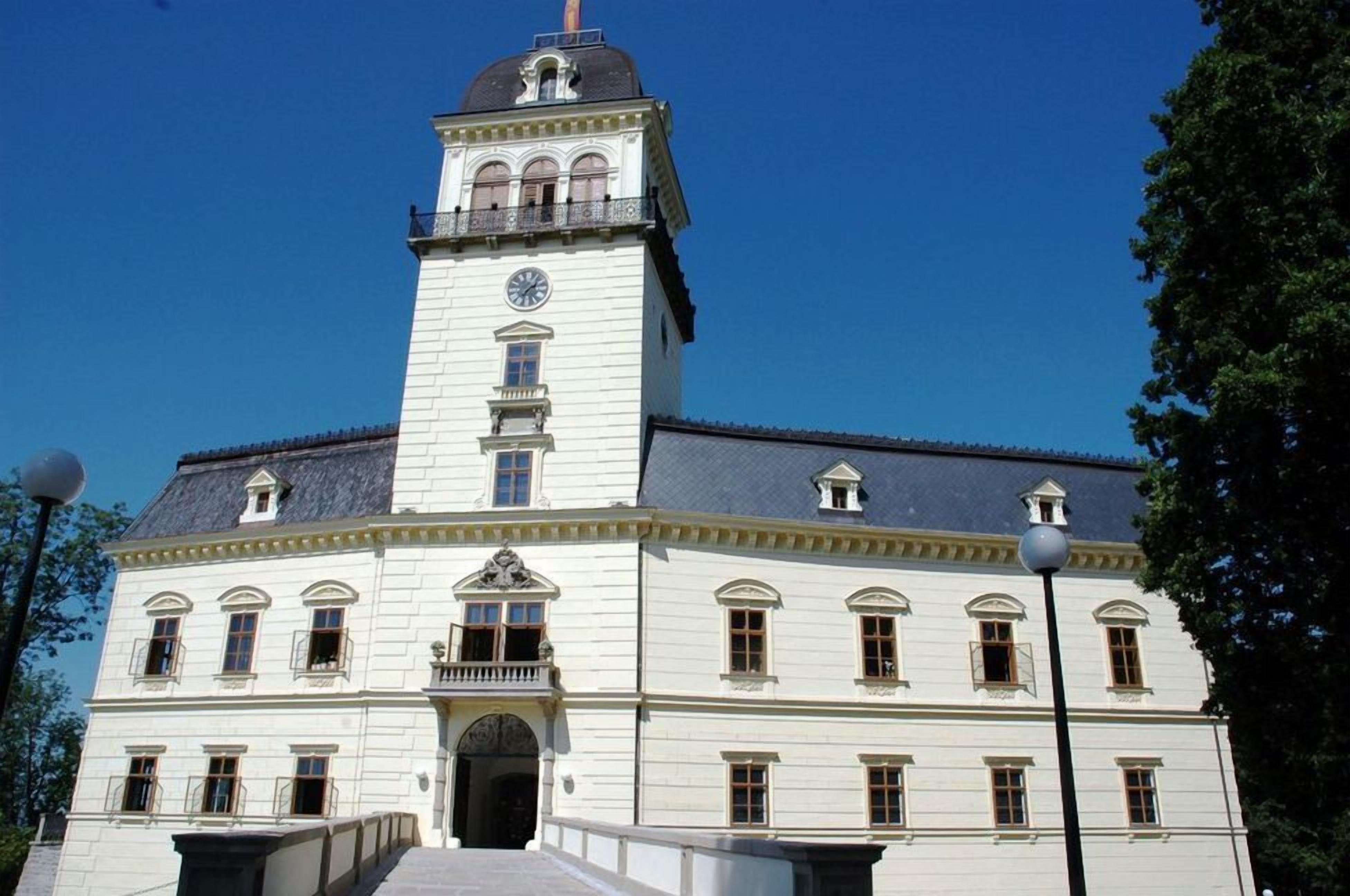 A large, white building with a prominent clock tower and multiple windows.