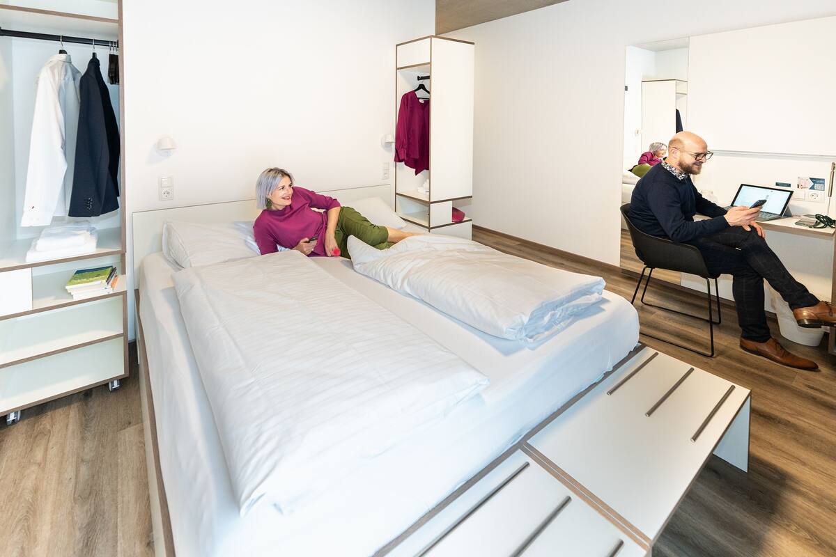 Une chambre d’hôtel moderne équipée d’un lit, d’un bureau et d’une armoire.