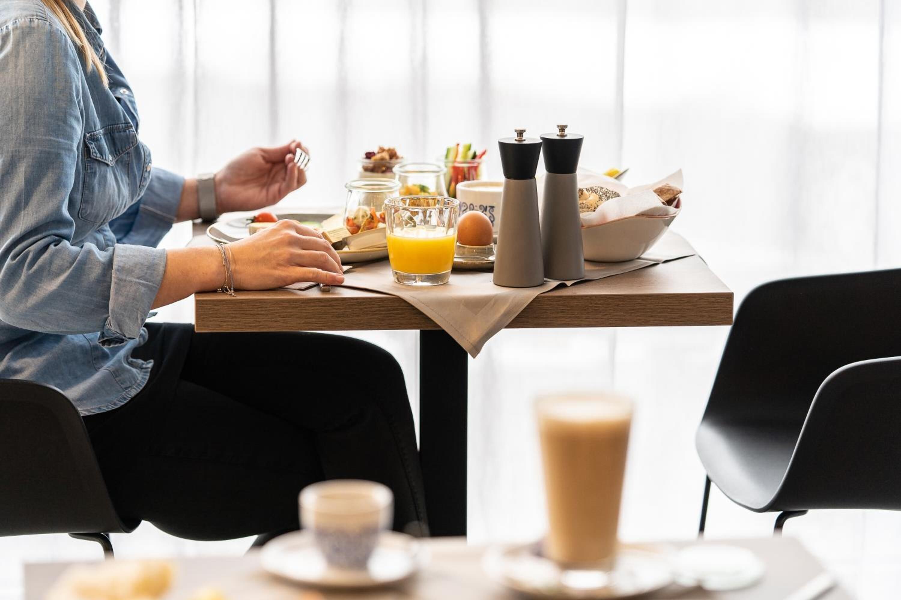 Una escena de desayuno con una mesa lista para dos personas, incluyendo un vaso de jugo de naranja, una taza de café y diversos alimentos para el desayuno.
