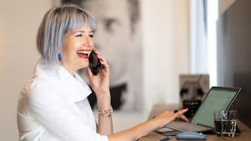 En person ved et skrivebord med en bærbar computer, et glas vand og en smartphone.