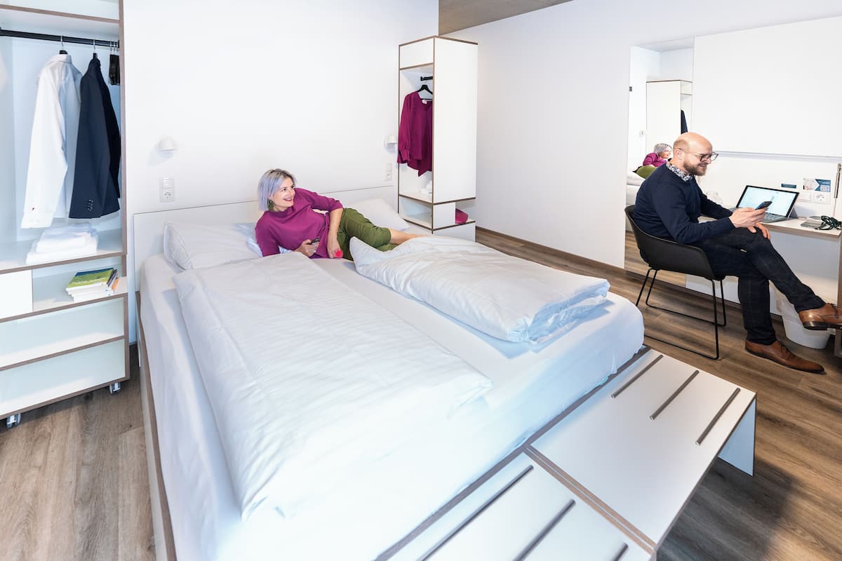 Une chambre d’hôtel moderne équipée d’un lit, d’un bureau et d’une armoire.