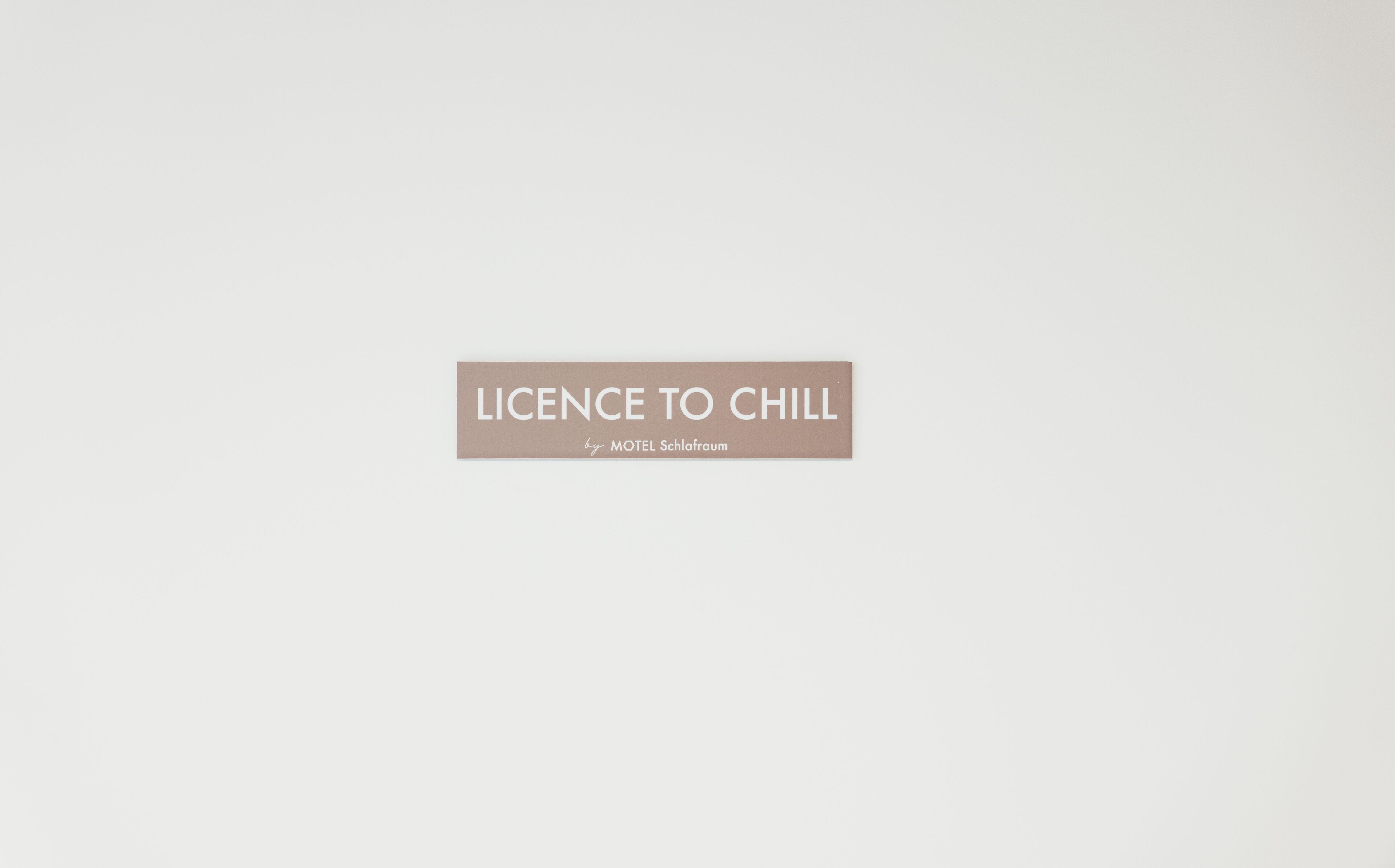 A sign with the text "LICENCE TO CHILL by MOTEL Schlafraum".