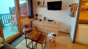 A small, cozy room with a wooden table and chairs, a television, and a small stool. - Avoriaz - Beautiful renovated apt for 4 people with wifi (Avoriaz)