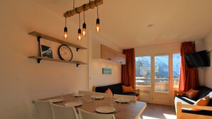 A dining area with a wooden table, white chairs, and a clock on the wall.