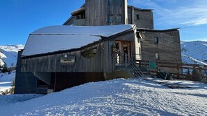 A wooden mountain lodge with a steep roof, a staircase leading to the entrance, and a sign reading "DATCHA".