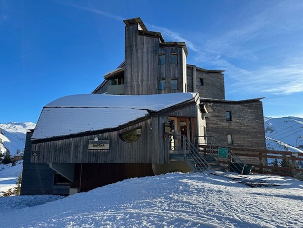 A wooden mountain lodge with a steep roof, a staircase leading to the entrance, and a sign reading "DATCHA".