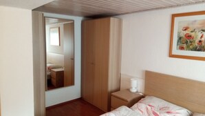 Quarto com cama, mesa de cabeceira, guarda-roupa, espelho e um quadro na parede.