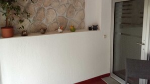 Um quarto com parede de pedra, uma planta em vaso e uma porta com painel de vidro.