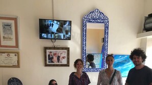 Een kamer met een blauwe bank, een spiegel met blauwe lijst, een televisie en een certificaat aan de muur.
