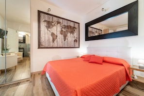 Un dormitorio con una cama grande, una obra de arte con un mapa del mundo, un espejo y una puerta de cristal que da a una sala de estar.