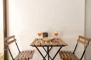 Una mesa de madera pequeña con dos sillas, un tazón de comida y dos vasos de jugo de naranja.