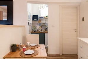 A narrow hallway leading to a kitchen with a tiled backsplash and a white door. - GuestHost - Bourbon House in Ortigia! (Syracuse)