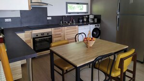 Una cucina moderna con zona pranzo, comprensiva di tavolo e sedie, lavatrice e frigorifero.