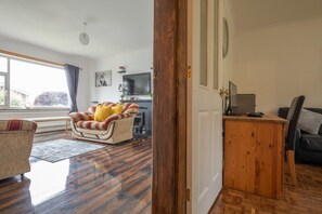 A living room with a sofa, a wooden coffee table, a television, and a fireplace. - 4-bed Detached, Pet Friendly House in Nelson (Nelson)