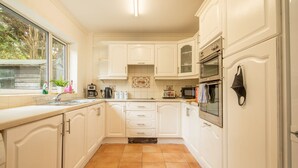 A kitchen with white cabinets, a tiled floor, a window, and a microwave. - 4-bed Detached, Pet Friendly House in Nelson (Nelson)