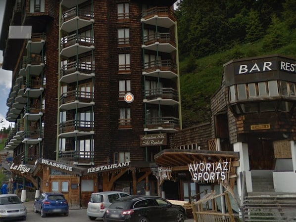 Un edificio de varios pisos con balcones, un restaurante y un bar.