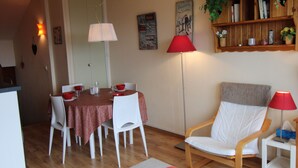 A dining area with a table set for four, a red and white patterned tablecloth, white chairs, and a red floor lamp. - Avoriaz - Duplex for 6 with balcony and WIFI (Avoriaz)