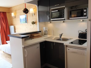 Una cocina compacta con un lavaplatos, dos microondas, una cafetera y un lavavajillas.