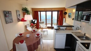 A compact living space with a dining area, kitchen, and a balcony with a view. - Avoriaz - Duplex for 6 with balcony and WIFI (Avoriaz)