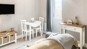 A bedroom with a bed, a desk, a chair, a TV, and a window. - The Rosebery Retreat By The Castle 1-bed Apartment (Inverness)