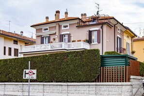 Stylish building with a balcony and a charming picket fence, set amidst a well-manicured hedge and a brick wall.