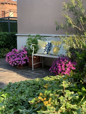 Relax in a serene garden setting with a comfortable bench surrounded by lush greenery and vibrant flowers.