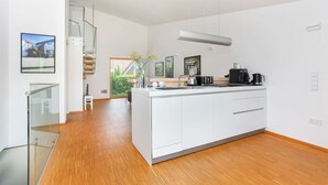 A modern kitchen with white cabinetry, a central island, and a built-in stove. - Contemporary bolthole, short walk from City Sleeps 2+1 (Canterbury)