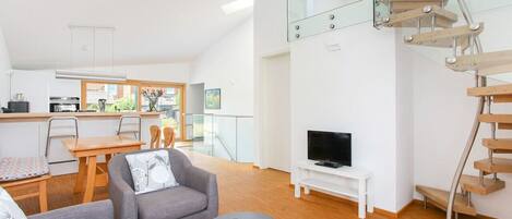 A modern apartment with a kitchen, dining area, living room, and a glass staircase.