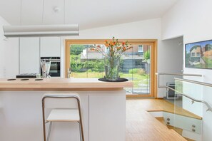 A modern kitchen with a large island, a built-in oven, and a view of a garden through a large window. - Contemporary bolthole, short walk from City Sleeps 2+1 (Canterbury)