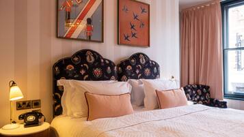 A neatly made bed with a patterned headboard, a bedside lamp, and a telephone on a wooden nightstand.