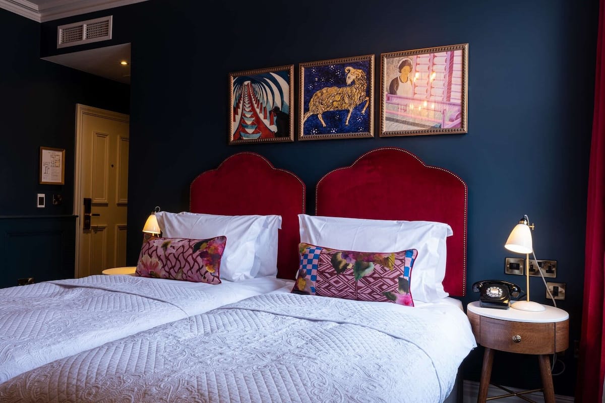A hotel room with a large bed, two bedside tables, and three framed artworks on the wall.