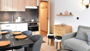 Eine moderne Küche mit Holzschränken, einem Esstisch mit Stühlen, einer Couch und einem Wandbild.