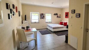 Une chambre moderne avec un lit, un bureau et une chaise. Il y a deux fenêtres et une porte.