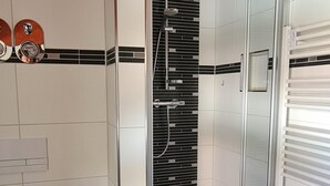 Une salle de bain avec douche, toilettes et porte-serviettes.