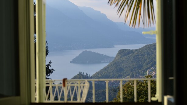 A view from a balcony overlooking a lake with mountains in the background.