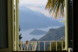 A view from a balcony overlooking a lake with mountains in the background. - Casa Lario (Naggio)