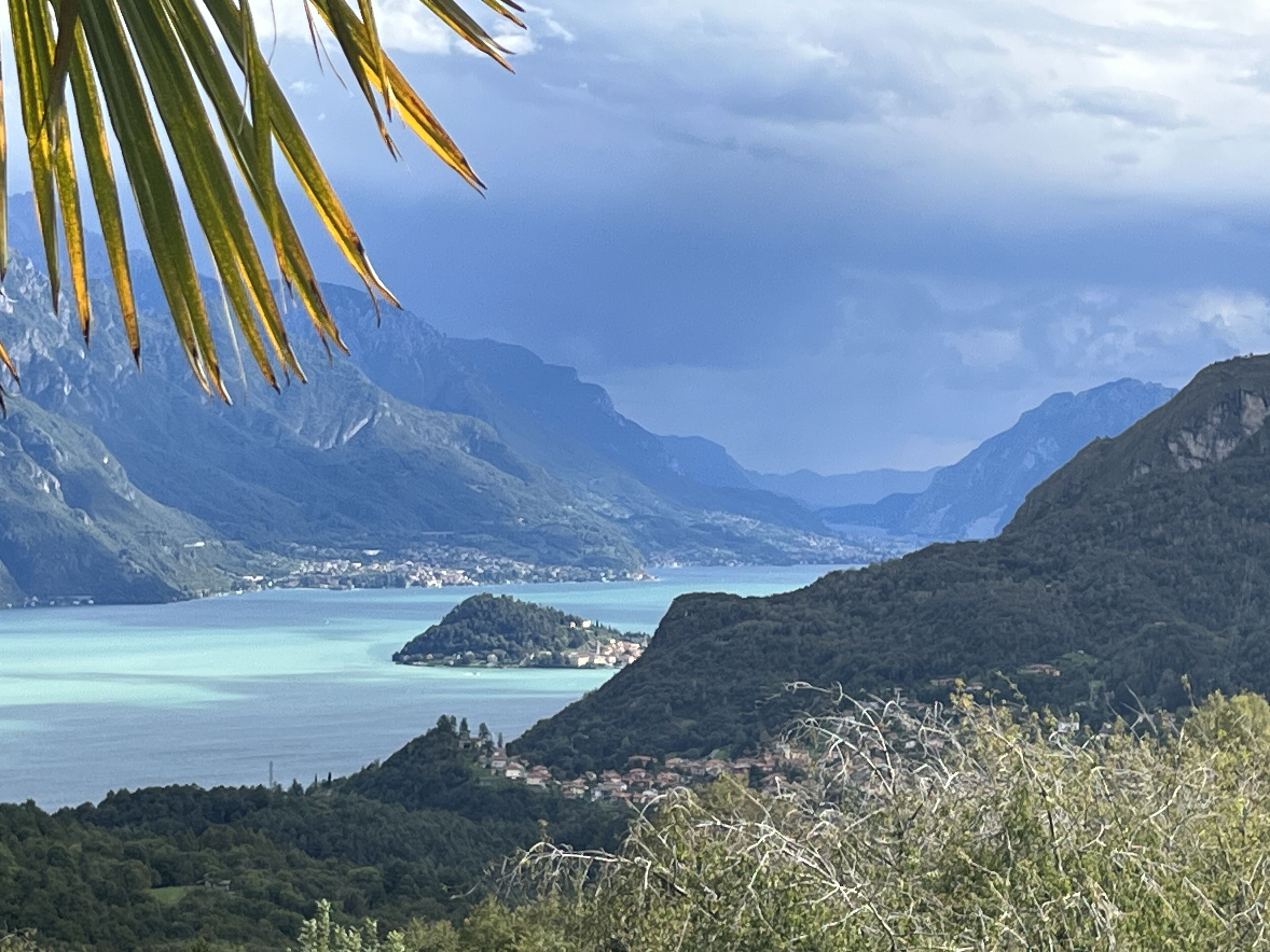 A coastal landscape with mountains, a small island, and a clear sky.