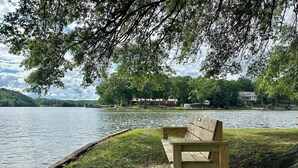 Un banc en bois au bord d’un lac, avec des maisons en arrière-plan.