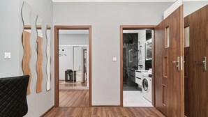 Ein Flur mit Holzboden, einem schwarzen Stuhl und einer Tür zum Waschraum.