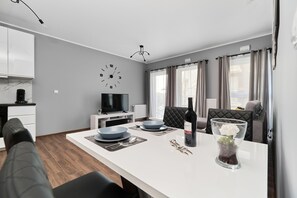Una sala de estar moderna con comedor, televisor y un reloj en la pared.