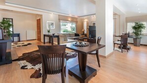 A spacious living area with a dining table, sofas, and a large window.