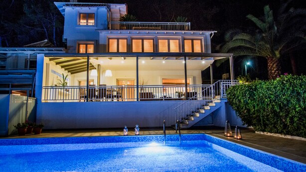 A modern two-story house with a swimming pool in front.