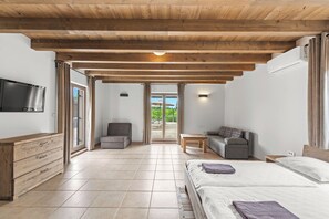 Un dormitorio moderno con techo de madera, una cama, un televisor y vistas al exterior.
