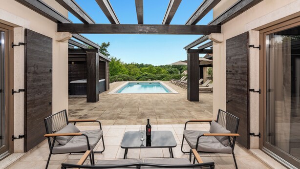 Un patio exterior con piscina, dos mesas y cuatro sillas.