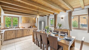 Una cocina espaciosa con armarios de madera, una isla grande y abundante luz natural proveniente de las ventanas.