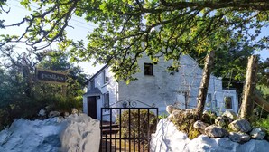 A white stone building with a black gate, surrounded by snow and trees. - Penllain (Newport)
