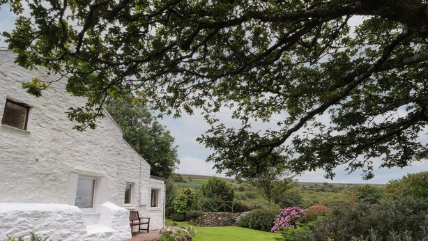 A white stone house with a small garden, a stone wall, and a bench. - Penllain (Newport)