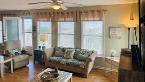 A living room with a ceiling fan, a sofa, a chair, a coffee table, and a lamp.